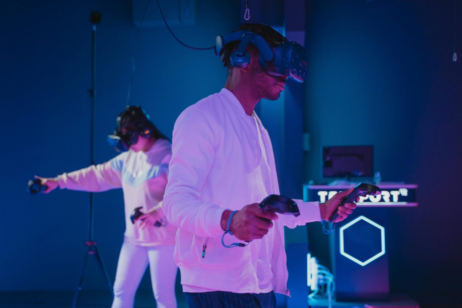 Two adults engaged in a virtual reality gaming session wearing VR headsets and controllers.